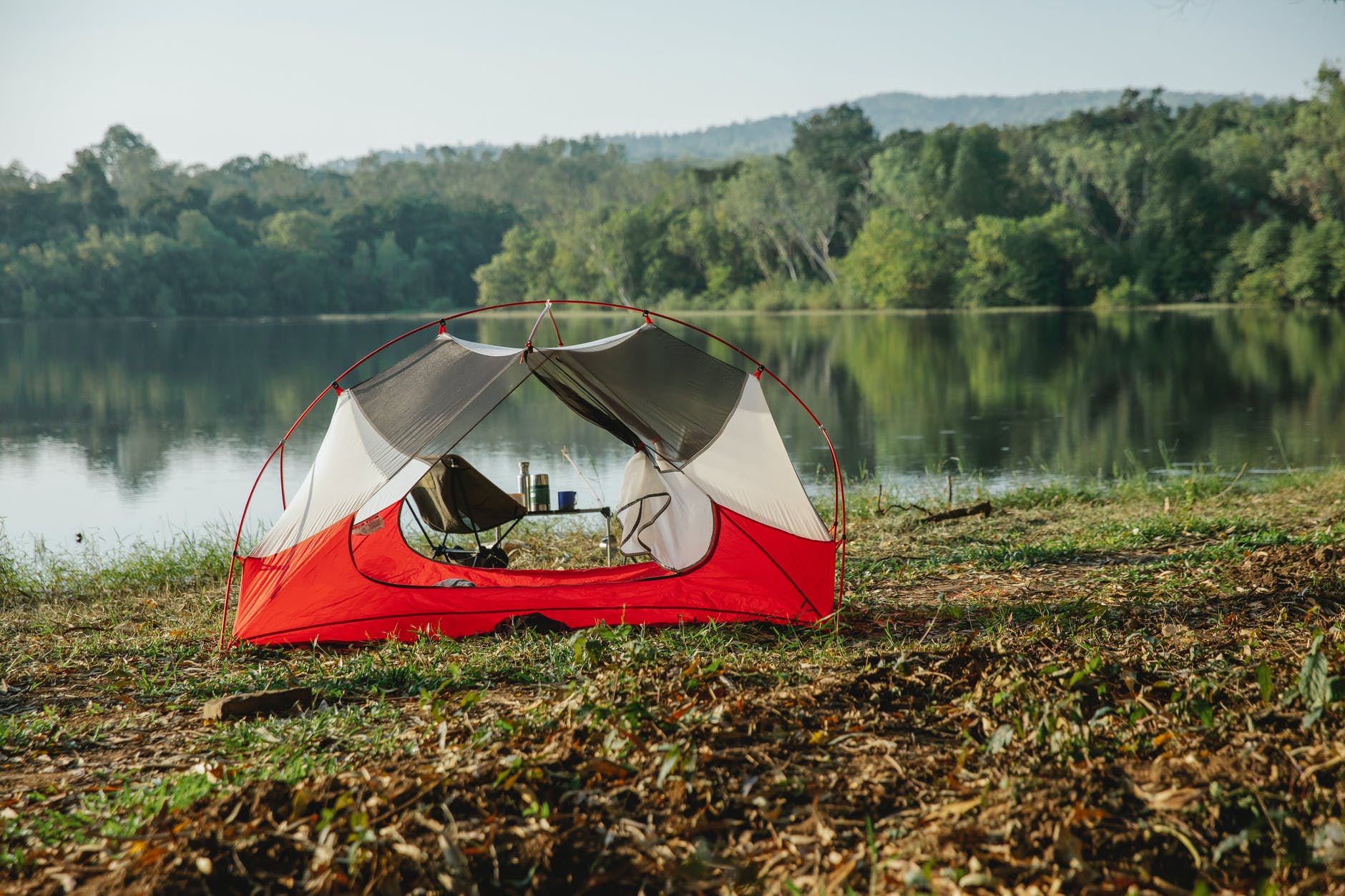 tent on river shore against lush trees