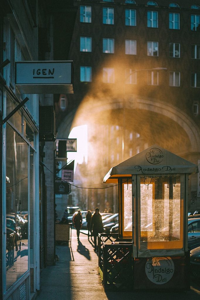 unrecognizable people walking along arched passage at sunrise