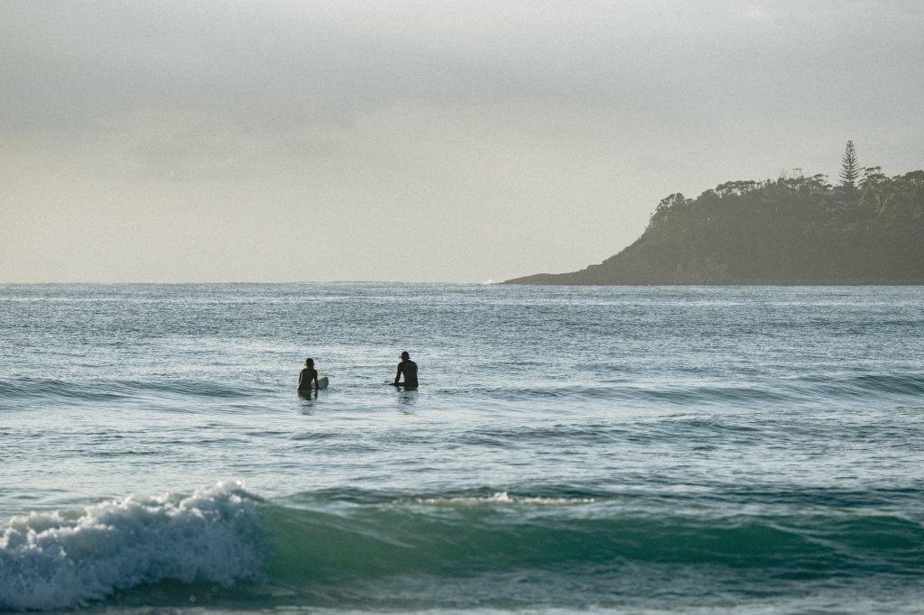 surfers swimming in rippling ocean in sunlight