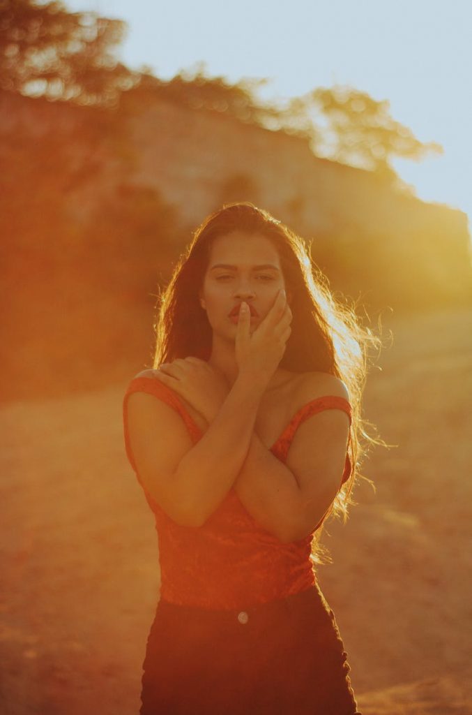 selective focus photography of red and black sleeveless dress with sun rays near trees