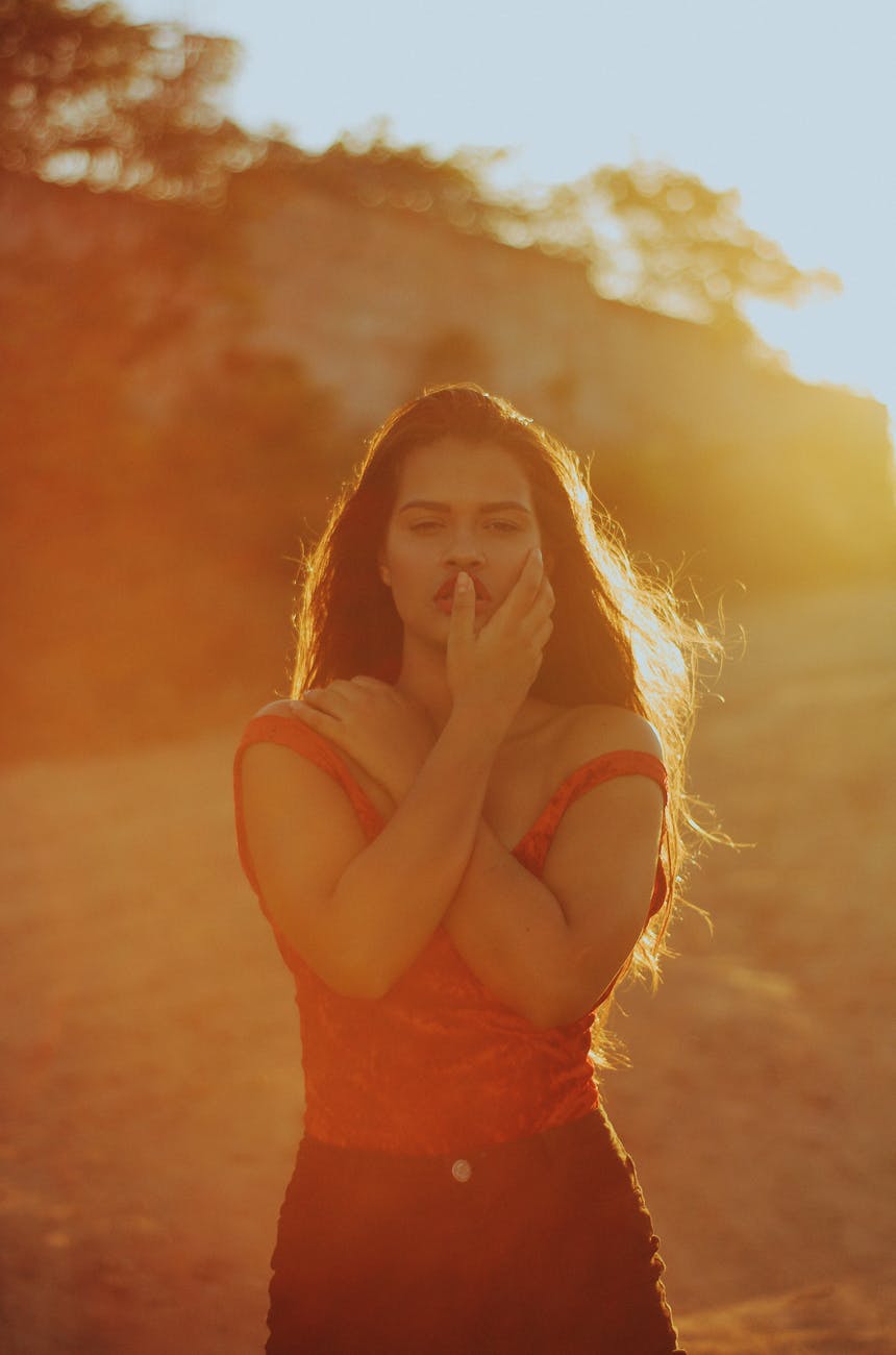 selective focus photography of red and black sleeveless dress with sun rays near trees