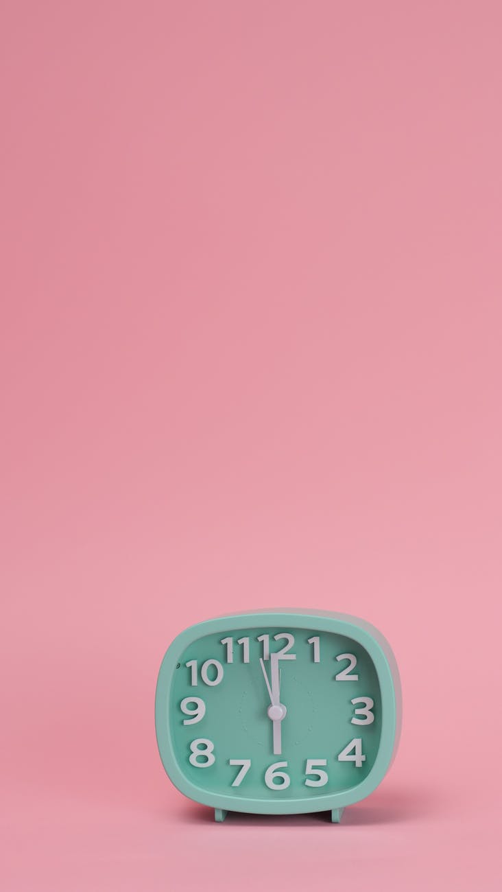 a green analog clock on pink background