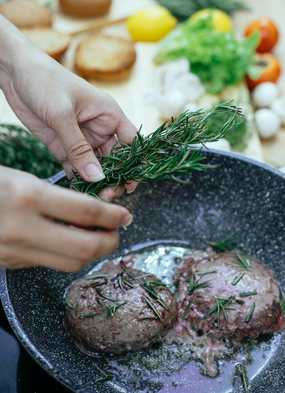 crop woman frying meat on pan